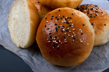 Yeast buns with sesame seeds on a gray background. Homemade bakery product. Close-up