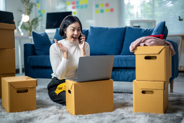 A woman is sitting on the floor in front of a laptop and talking on the phone