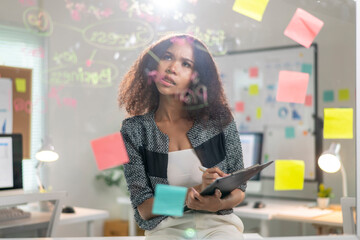 A woman is sitting at a desk with a clipboard and a pen