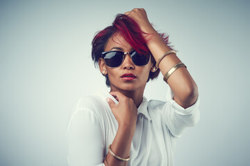 Portrait, fashion and woman with sunglasses, confidence and person on gray studio background. Face, model and girl with stylish clothes, hair dye and mockup space with pride, punk rock and gen z