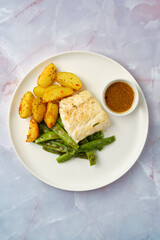 Delicious roasted potatoes and green beans with seasoned fish on a plate