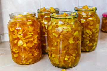 Glass jars with apple jam on kitchen table before closing with lids for preservation.