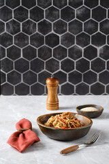 Delicious spaghetti with pulled beef and fresh ingredients served in a rustic bowl on a marble countertop