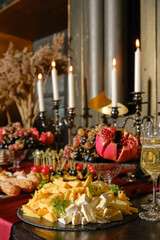 Elegant dining table set with cheese, fruits, and candles for a festive evening gathering
