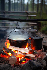 Cooking on a camping trip. A pot of boiling water is hanging over a fire.