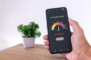 Man in room checking air quality index using a smartphone