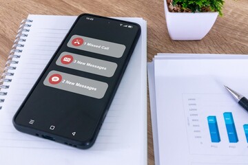 A smartphone on a office desk with missed call and new message notification on the phone screen