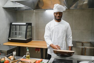African American male chef frying vegetables in restaurant kitchen