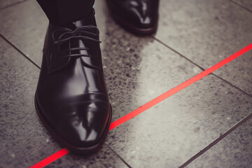 Legs of a formally dressed man at the red line, copyspace