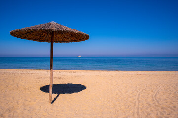 sandy beach with reed sun umbrella