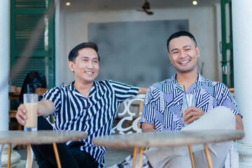 Two friends sit in a trendy cafe, sharing drinks and smiles, enjoying the lively atmosphere
