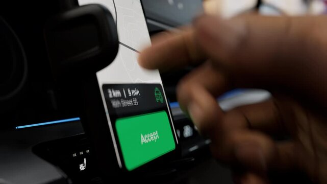 A ride-share or taxi driver uses a ride-hailing app to accept a passenger request. The phone screen displays a map and route, highlighting the app's functionality for managing rides efficiently