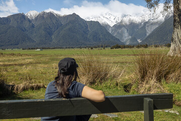 Woman sitting on bench looking at Franz Josef Glacier