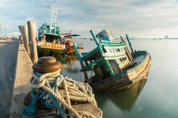 Chonburi, Thailand - May, 26, 2024 : Abandoned Fishing Boat Sinking in Harbor in sunrise at...