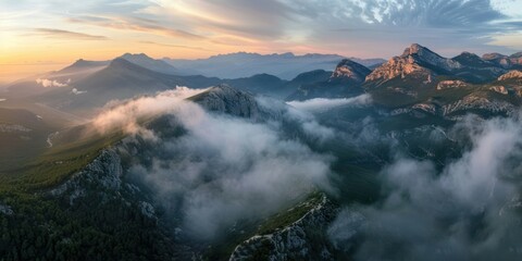 Naklejka premium Aerial view of mountain ranges covered in mist at sunrise.