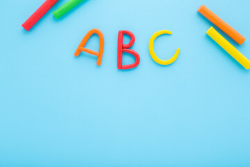 Colorful abc letters created from modeling clay on light blue table background. Pastel color. Time...