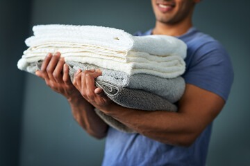Hands, laundry and pile with man in studio on gray background for chores or spring cleaning....
