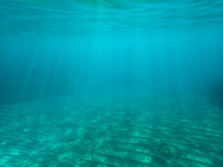 Ocean blue underwater with sunrays, Underwater Sea Deep Water Abstract Sunshine, sea wave , clean waters in summer time, Natural underwater seascape, sand on ocean floor and water surface with sunligh