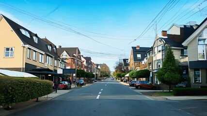 A quiet residential street transitions into a lively urban district under clear skies.