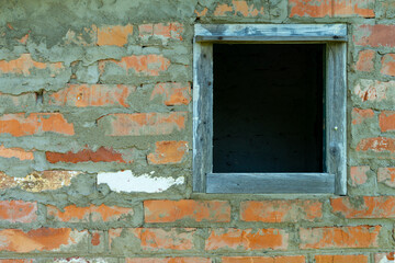 Fototapeta premium A wooden frame in a brick wall of an abandoned house