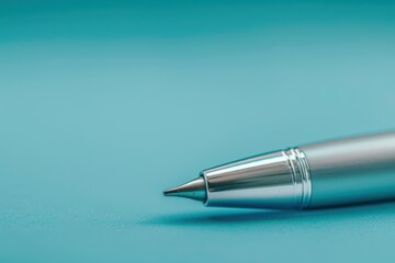 Silver pen resting on a turquoise desk surface, close-up view