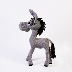 Amigurumi doll gray donkey stands background white isolated