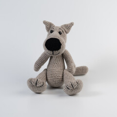 Amigurumi doll wolf gray sits there white isolated