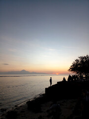 silhouette of a person standing on a pier at sunset © idon alrastani