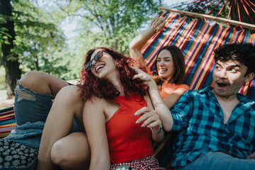 Three friends enjoying a fun and relaxed moment together on a vibrant hammock in a beautiful sunny...