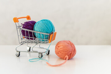 Wool yarn balls in small shopping cart. Purchase of knitting materials. Free space for text