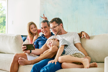 Gay dad, children and selfie in home on sofa with hug, peace sign and connection with memory in living room. Father, kids and lgbtq parents with icon, care and bunny ears on couch in family house