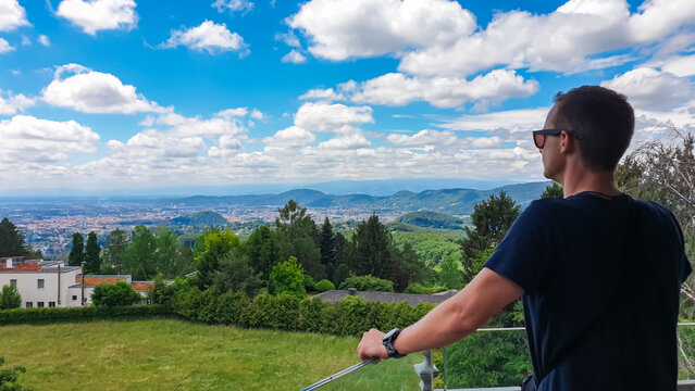 Rear view of man overlooking city of Graz seen from Stefanienwarte Platte in Styria, Austria, Europe. Natural getaway in Mariatrost on sunny summer day. Aerial vistas on urban landscape. Outdoor