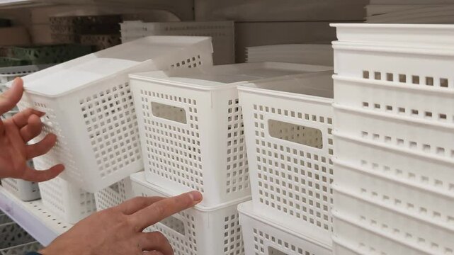 Man chooses plastic container at hardware store. Customer holding small plastic box for different kind of fasteners. White box for nails, bolts and screws. Small basket for different things at home