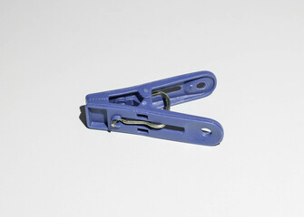 A blue clothespin, lying on a white background