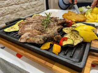 grilled ribs with vegetables and lemon on the table on a cast iron tray