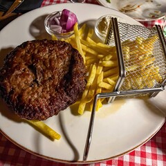 Cutlet and French fries in a basket next to purple onion and kajmak. Serbian cuisine