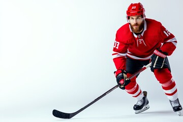 A focused hockey player in red gear, poised for action on the ice. His intense expression and athletic stance convey the competitive spirit of the game.