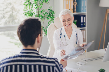 Photo of aged woman qualified doctor show x-ray patient man wear white coat workplace office indoors