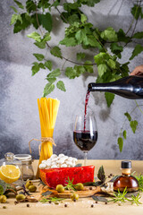 Someone pouring red wine into glass for italian style dinner preparation