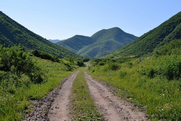 A tranquil dirt road winds through lush green hills on a sunny day in the countryside