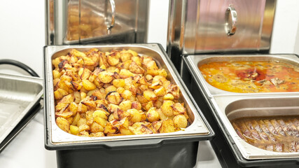 A buffet table with roasted potatoes  at a catering event