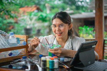 asian woman painting handmade plastic bottle craft using brush