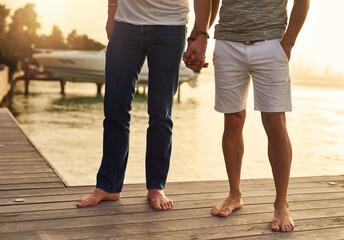 Holding hands, travel and gay couple by pool on vacation, getaway or weekend trip for romance. Love, boardwalk and legs of queer men in relationship with connection, bonding or care at holiday resort