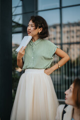 A confident woman in a striped shirt holds papers while attending an outdoor meeting. She appears engaged and attentive, showcasing professionalism and communication skills.