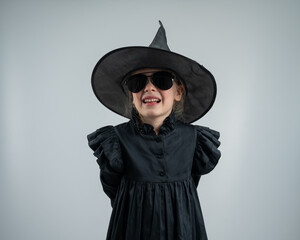 Fototapeta premium Portrait of a little Caucasian girl in a witch costume on a white background. 