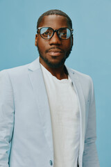 Stylish African man wearing glasses and a light blue blazer, posing confidently on a solid blue background, exuding elegance and modernity, perfect for fashion and lifestyle concepts