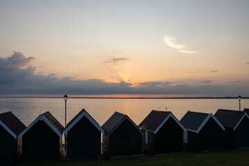 Beach huts at Gurnard, Cowes, Isle of Wight at sunset.  Looking over the western Solent