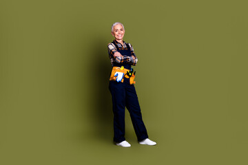 Fototapeta premium Full size photo of senior female professional expert handyman crossed hands wear blue workwear overall isolated on khaki color background