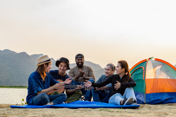 diverse group of friends  having fun when they are camping by the pond,asian family and the african...