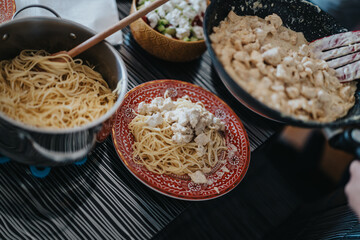 A home-cooked pasta dish featuring creamy chicken on a red plate, accompanied by a fresh salad. Perfect for family dinners and gatherings, showcasing comfort and flavor.